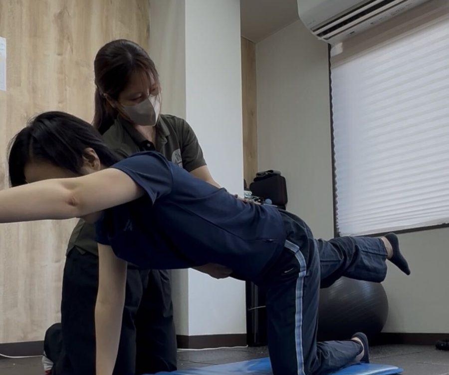マットの上で体幹トレーニングをする女性とトレーナー